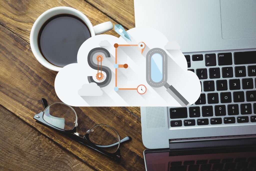 Top view of cloud with a word seo, cup of tea, glasses and laptop on the table