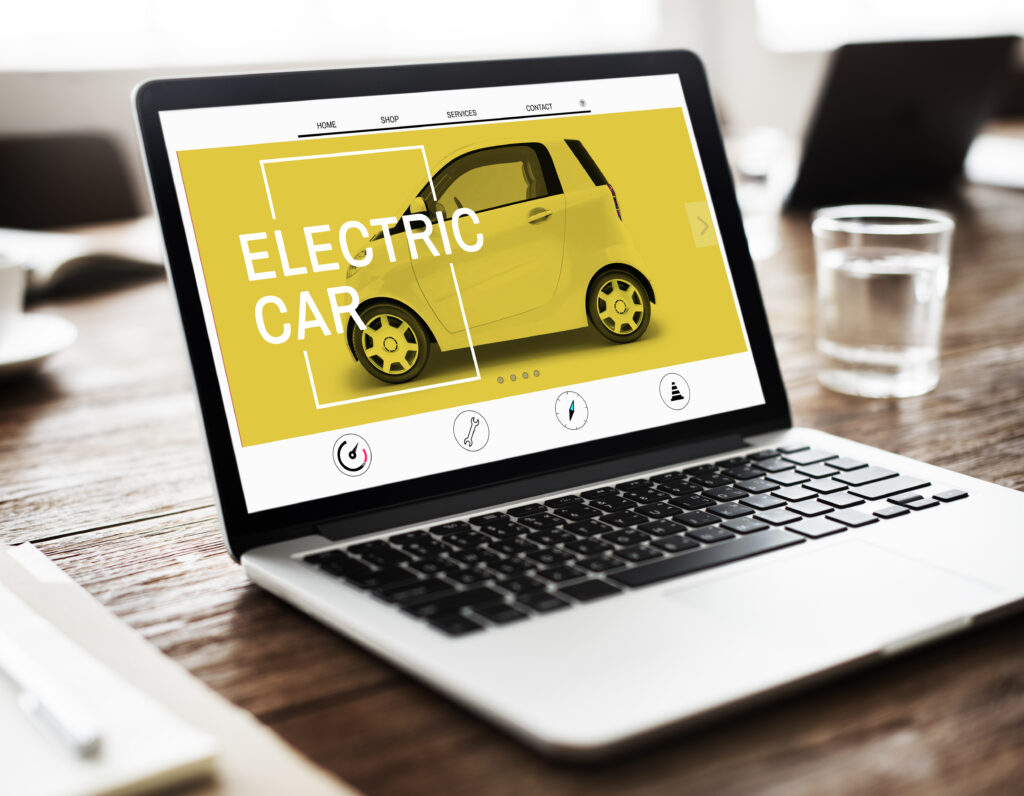 Laptop with a website opened for automotives and galss beside on a table