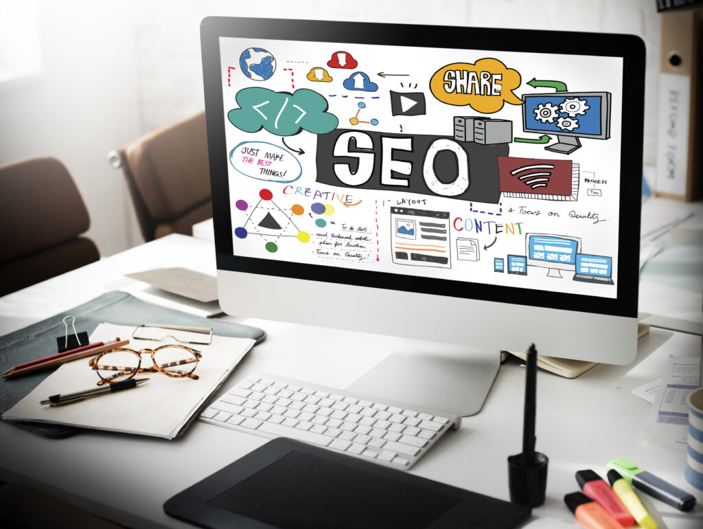 Screen representing seo strategies with glasses, pens, papers on the desk