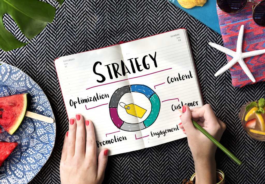 girl's hand holding pencil pointing toward a book on which strategies are written