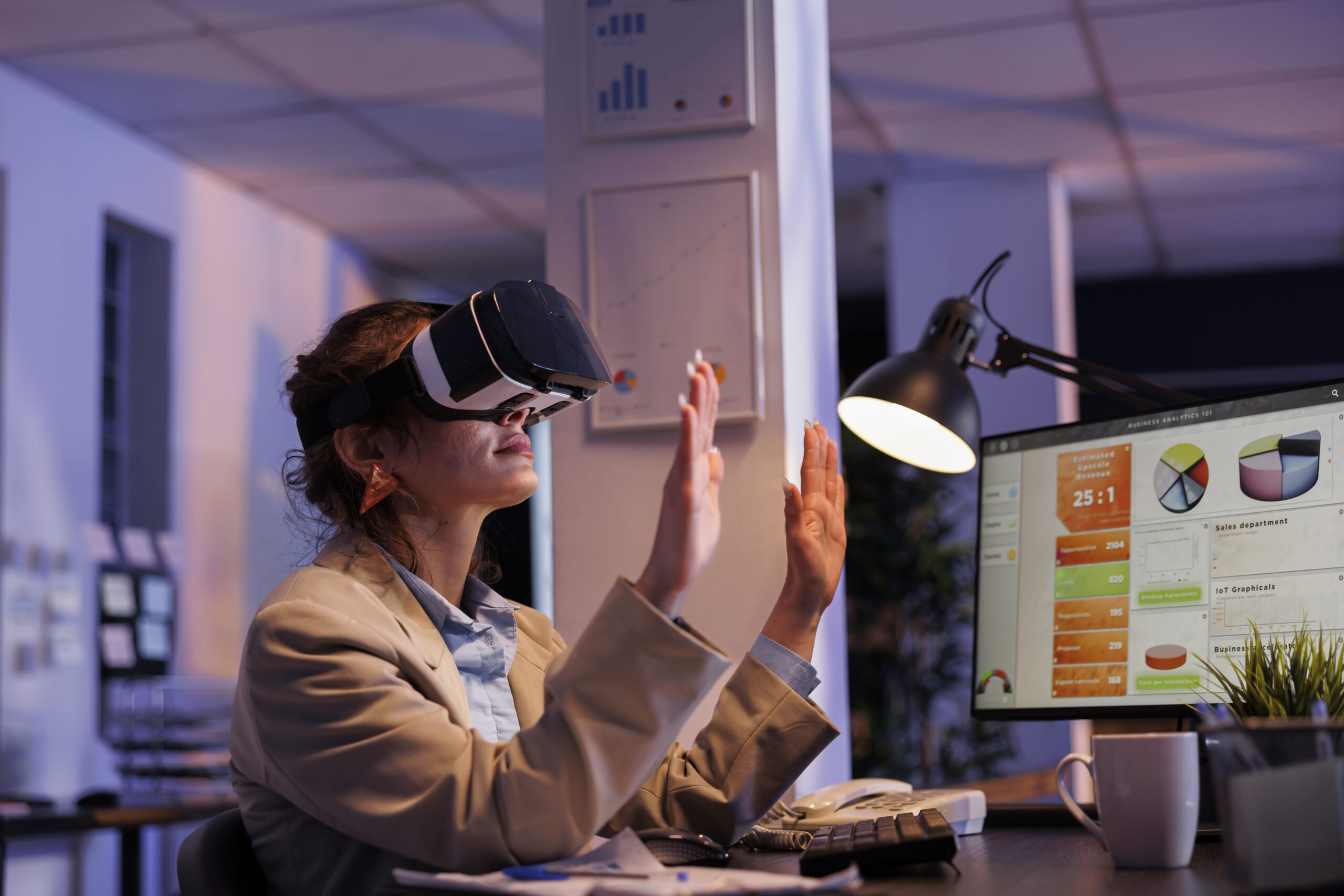 Corporate employee planning financial investment strategy usinh hologram, to increase company profit. Businesswoman wearing virtual reality headset, working late at night in startup office