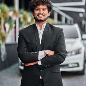 Indian businessman in the background of his white car.